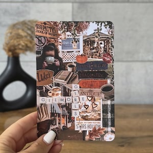 Può includere: Una carta rettangolare con un collage di immagini di Gilmore Girls, inclusi testi come Stars Hollow, Luke's e Miss Patty's School of Ballet. Il design incorpora temi autunnali, tazze di caffè, libri e tessere di Scrabble che compongono Gilmore Girls.