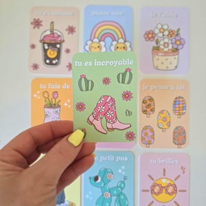 Peut inclure: Ensemble de cartes illustrées avec du texte en français. Les cartes présentent des images d'un arc-en-ciel, de fleurs, d'une boisson et d'un chien ballon. Une carte indique "tu es incroyable" en texte blanc. Les cartes sont de couleurs pastel.