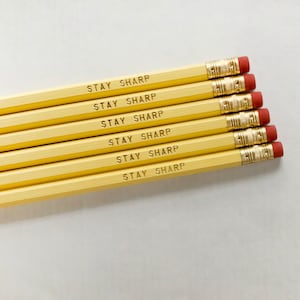 Puede incluir: Seis lápices amarillos con gomas de borrar rojas. Cada lápiz tiene las palabras "STAY SHARP" impresas.