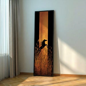 May include: A framed art print featuring a silhouette of a rearing horse against a sunset backdrop. The artwork has a black frame, with tall grass in the foreground and a warm, orange and yellow gradient in the background. The horse is black.