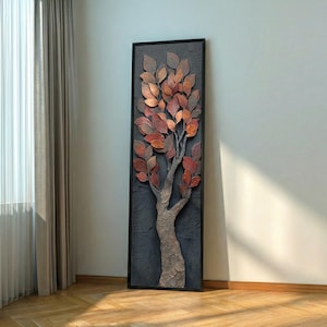 May include: A framed wall art piece featuring a textured tree with copper and red leaves. The tree's trunk is a textured, light brown color, set against a dark gray background. The artwork is in a black frame.