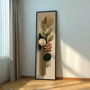 Può includere: Opera d'arte astratta da parete con cornice nera e sfondo beige. L'opera presenta forme geometriche, un ramo con foglie e una sezione a strisce verticali. I colori includono verde, marrone e beige.