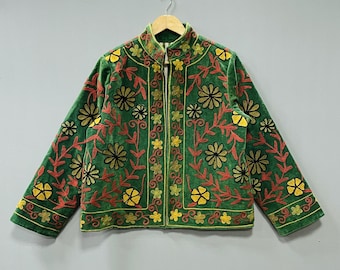 May include: Green velvet jacket with floral embroidery in red, yellow, and black. The jacket has a stand-up collar and a full-length zipper. The floral design is repeated across the jacket's front, back, and sleeves.