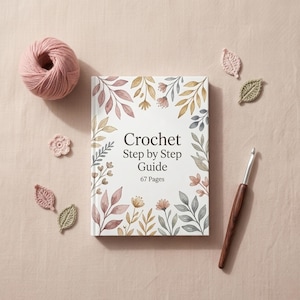 Puede incluir: Una guía de ganchillo paso a paso con 67 páginas, una madeja de hilo rosa, un ganchillo y varios adornos de hojas y flores de ganchillo. La portada del libro presenta ilustraciones florales en colores suaves, creando una imagen artesanal.