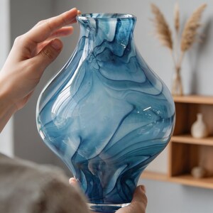 May include: A decorative glass vase with a unique blue and white swirl pattern. The vase has a bulbous body and a flared top. The colors and design create a flowing, artistic look. This vase is suitable for home decor.