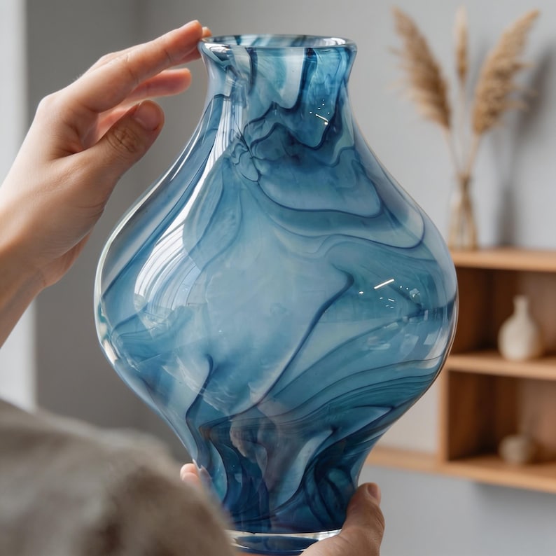 May include: A decorative glass vase with a unique blue and white swirl pattern. The vase has a bulbous body and a flared top. The colors and design create a flowing, artistic look. This vase is suitable for home decor.