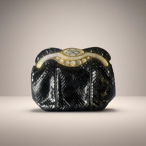 Peut inclure: Une pochette noire avec un motif texturé en forme de peau de serpent. Le fermoir est doré et orné de strass. Le sac a une forme incurvée et un design structuré, adapté aux événements formels.