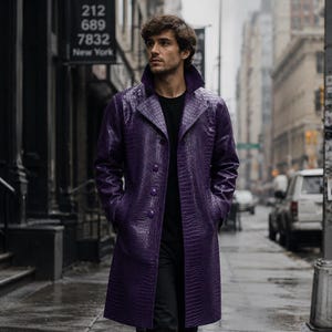 May include: A long, purple coat featuring a textured crocodile-skin pattern, a wide collar, and a button-front closure. The coat is worn over a plain black shirt. The garment has long sleeves and a structured fit, extending to the mid-thigh area.
