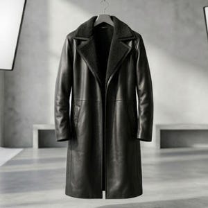 Puede incluir: Un abrigo largo de cuero negro con solapas y forro de borrego. El abrigo está colgado de una percha de madera sobre un fondo neutro de estudio. El abrigo parece ser un diseño clásico y atemporal.
