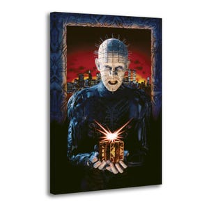 May include: A rectangular canvas print featuring a pale, bald figure with pins protruding from the head and face, wearing a dark, textured suit. The figure holds a glowing, ornate golden cube. A dark city skyline sits against a red sky background.
