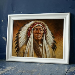 May include: A framed painting of a Native American person wearing a traditional feathered headdress with white and black feathers and red accents. The portrait features a tan background and is enclosed in a white rectangular frame.