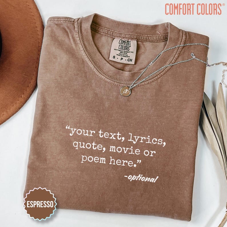 以下が含まれることがあります： クルーネックの茶色の半袖Tシャツで、Comfort Colorsのブランドラベルが付いています。Tシャツには「your text, lyrics, quote, movie or poem here.」という白いプリント文字があり、その下に「-optional」と書かれています。