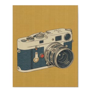 May include: A vintage-style rangefinder camera illustration featuring a dark blue body with silver accents, a prominent lens, and a small red button detail. The camera is set against a textured mustard yellow background with a grid-like pattern.