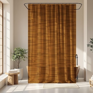 May include: A mustard-colored shower curtain with a linear pattern of thin, dark brown horizontal and vertical lines. The curtain hangs from a black curved rod in a bathroom setting. The room has large windows and potted plants.