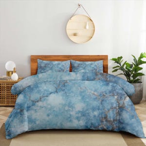 May include: A bedding set featuring a duvet cover and two matching pillowcases with a blue and white marble-like pattern. The design displays a cloudy, textured aesthetic with dark grey veining throughout the fabric, covering the entire bed.