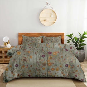 May include: A bedding set featuring a duvet cover and two matching pillow shams with a muted sage green background. The fabric is decorated with a repeating pattern of delicate, thin-stemmed wildflowers in shades of yellow, orange, and purple.