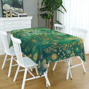 May include: A rectangular tablecloth featuring a vibrant green and teal abstract pattern with circular, gold-toned, and earthy brown organic shapes scattered across the surface, draped over a table surrounded by four white wooden chairs.