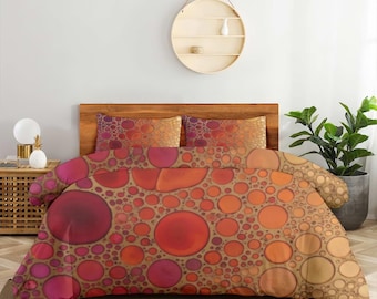May include: A bedding set featuring a duvet cover and two pillowcases with a repeating pattern of circles in various sizes. The design displays a gradient of warm colors, including deep red, bright orange, and soft peach, set against a tan background.