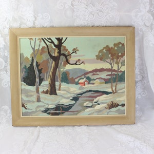 May include: A framed painting of a winter landscape with a stream, trees, and two houses. The painting is done in a stylized, almost cartoonish style, with bright colors and simple shapes. The houses are red and yellow, and the trees are brown, green, and white.