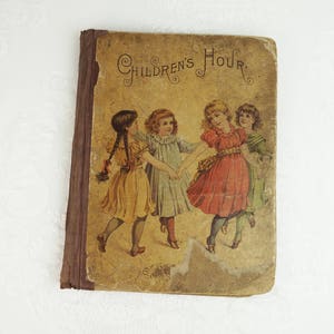 May include: Vintage children's book cover with the title "Children's Hour" in ornate lettering. The cover features an illustration of four girls in dresses, holding hands and dancing in a circle.