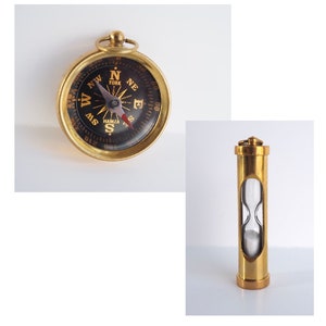 May include: A vintage-style compass with a gold-colored casing and a black face, displaying directional markings. Next to it is a gold-colored hourglass with a clear glass center filled with white sand. The compass has the word "York" on it.
