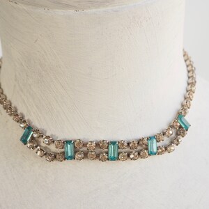 May include: A silver choker necklace with a double row of clear rhinestones and a row of rectangular turquoise blue stones.