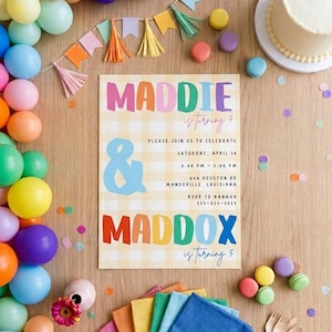 Puede incluir: Una tarjeta de invitación de cumpleaños con fondo de cuadros vichy amarillos con el texto MADDIE is turning 7 y MADDOX is turning 5, rodeada de globos coloridos, un pastel, macarons, servilletas y cubiertos de madera sobre una superficie de madera.