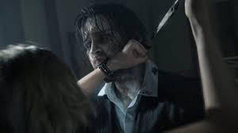 Puede incluir: Una escena oscura y dram&aacute;tica con una persona vestida con un traje oscuro y una camisa azul claro. Una mano con un reloj est&aacute; levantada, con un cuchillo apuntando al cuello de la persona. La imagen transmite una atm&oacute;sfera intensa y de suspense.