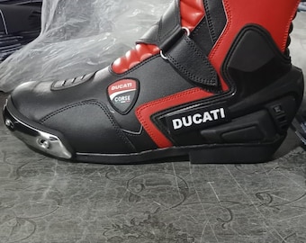 May include: Black and red motorcycle boot with the "Ducati" logo. The boot has a high-top design with a reinforced heel and toe. The boot is made of leather and has a sleek, modern look.