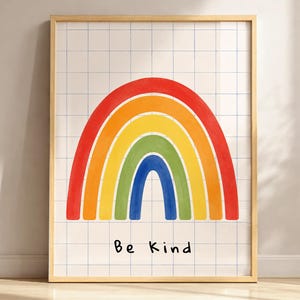 Può includere: Una stampa artistica da parete incorniciata raffigurante un arcobaleno in stile dipinto a mano con archi rossi, arancioni, gialli, verdi e blu. Lo sfondo è costituito da una griglia bianca con sottili linee blu. Il testo "Be Kind" è stampato in nero.