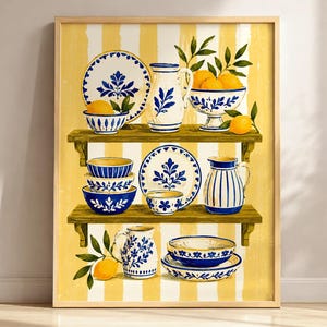 May include: A framed wall art print featuring two wooden shelves against a yellow and white striped background. The shelves hold blue and white ceramic plates, bowls, and pitchers decorated with floral patterns, accompanied by yellow lemons.