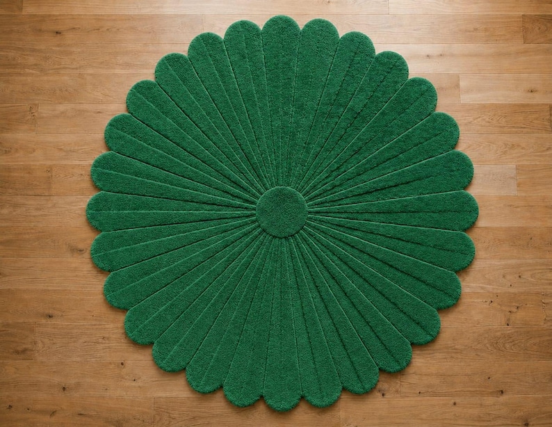 Puede incluir: Una alfombra circular de color verde intenso s&oacute;lido, con una superficie texturizada que presenta un patr&oacute;n radial de segmentos alargados en forma de p&eacute;talos que se extienden desde un n&uacute;cleo central circular, creando una silueta de flor.