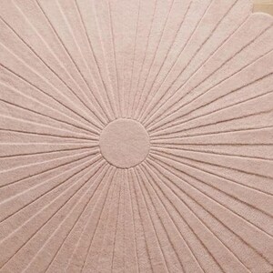 A close-up view shows the center and textured petal details of a pale pink scalloped flower rug.