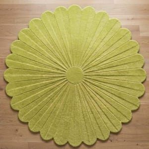 Puede incluir: Una alfombra circular de color verde lima vibrante, con una superficie texturizada y un patr&oacute;n radial de segmentos alargados en forma de p&eacute;talos que se extienden desde un centro circular s&oacute;lido, creando una silueta en forma de flor.