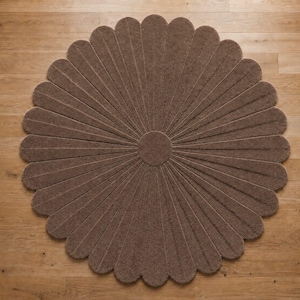 Puede incluir: Una alfombra circular marr&oacute;n con forma de flor, compuesta por numerosos p&eacute;talos alargados y redondeados que irradian desde un centro circular s&oacute;lido. La alfombra presenta una superficie texturizada y copetuda, dispuesta en un dise&ntilde;o floral.