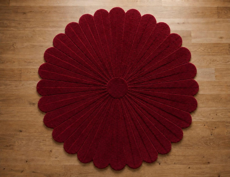 Puede incluir: Una alfombra circular de color rojo intenso con forma de flor, compuesta por numerosos p&eacute;talos redondeados que irradian desde un disco central s&oacute;lido. La alfombra presenta una superficie texturizada y est&aacute; extendida en plano.
