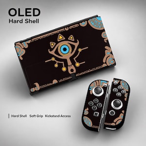 Pode incluir: Capa rígida preta e skins de controlador para consola de jogos OLED. A capa e os controladores apresentam um design castanho, azul e dourado com um símbolo de olho. O texto "OLED Hard Shell" está no topo.