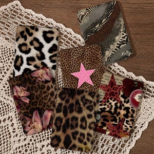 May include: A collection of six rectangular covers featuring various animal print patterns, including leopard and zebra designs. Some covers display decorative elements like a bright pink star, pink lily flowers, red roses, a billiard ball, and the name Kelly.