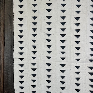 Könnte beinhalten: Weißer Stoff mit einem sich wiederholenden Muster aus schwarzen Dreiecken. Die Dreiecke sind in vertikalen Reihen angeordnet.