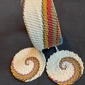 May include: A set of white woven earrings and a bracelet with a multi-colored striped design. The earrings are round and have a spiral pattern. The bracelet is wide and has a straight design.