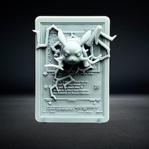 Può includere: Una carta Pokémon grigia stampata in 3D con un design Pikachu che emerge dalla superficie. La carta presenta testo e il numero 20. Pikachu ha dei fulmini intorno.