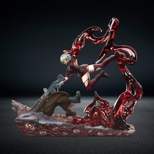 May include: A detailed figurine depicting a dynamic action scene. A woman in a maroon outfit is reaching for a person holding a rifle. The base and surrounding elements are a deep red, with a dark background.