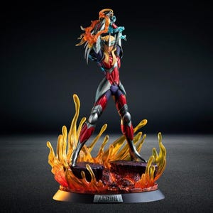 May include: A detailed figurine of a character in a red, silver, and blue armored suit, holding energy effects. The figure stands on a rocky base surrounded by orange and yellow flames, with the name "HAGEN" on the base.