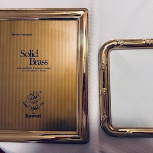 May include: A rectangular solid brass picture frame with a tarnish-resistant lacquer coating, measuring 8 inches by 10 inches, alongside a smaller, rounded rectangular gold-toned metal picture frame featuring a decorative bamboo-style border.