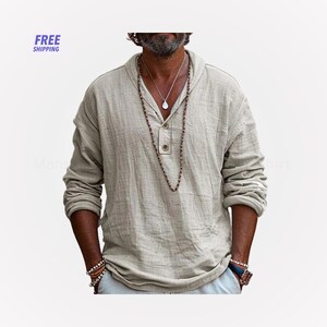 Peut inclure: Une chemise beige clair &agrave; manches longues avec un col Henley et trois boutons en bois. La chemise a une coupe d&eacute;contract&eacute;e et est faite d'un tissu textur&eacute;. L'image montre &eacute;galement un collier et des bracelets.
