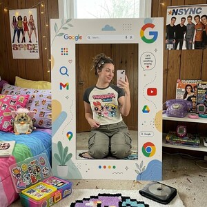 以下が含まれることがあります： 白い背景にカラフルなGoogleアイコン、検索バー、植物や雲の装飾グラフィックが施された大きな長方形の鏡用フレーム。フレームにはGoogleロゴ、Gmail、YouTube、Drive、Chromeのアイコンが表示されています。