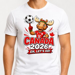 May include: A white t-shirt featuring a cartoon moose wearing a red jersey with the number 26 and a maple leaf. The moose spins a soccer ball on its finger. Below, the text reads CANADA 2026 and EH, LET'S GO! on a red banner graphic.