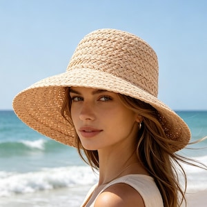 May include: A light beige woven straw hat with a rounded crown and a wide, slightly downturned brim. The hat features a textured, braided straw pattern throughout, providing a natural, neutral appearance suitable for sunny outdoor environments.