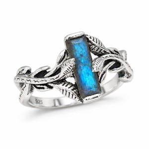May include: A sterling silver ring featuring a rectangular, faceted labradorite gemstone with blue iridescence. The band is designed with detailed, raised leaf and vine motifs wrapping around the stone. The interior of the band is stamped with 925.