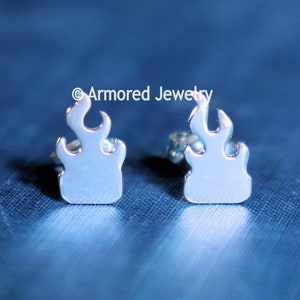 May include: A pair of silver flame-shaped stud earrings.